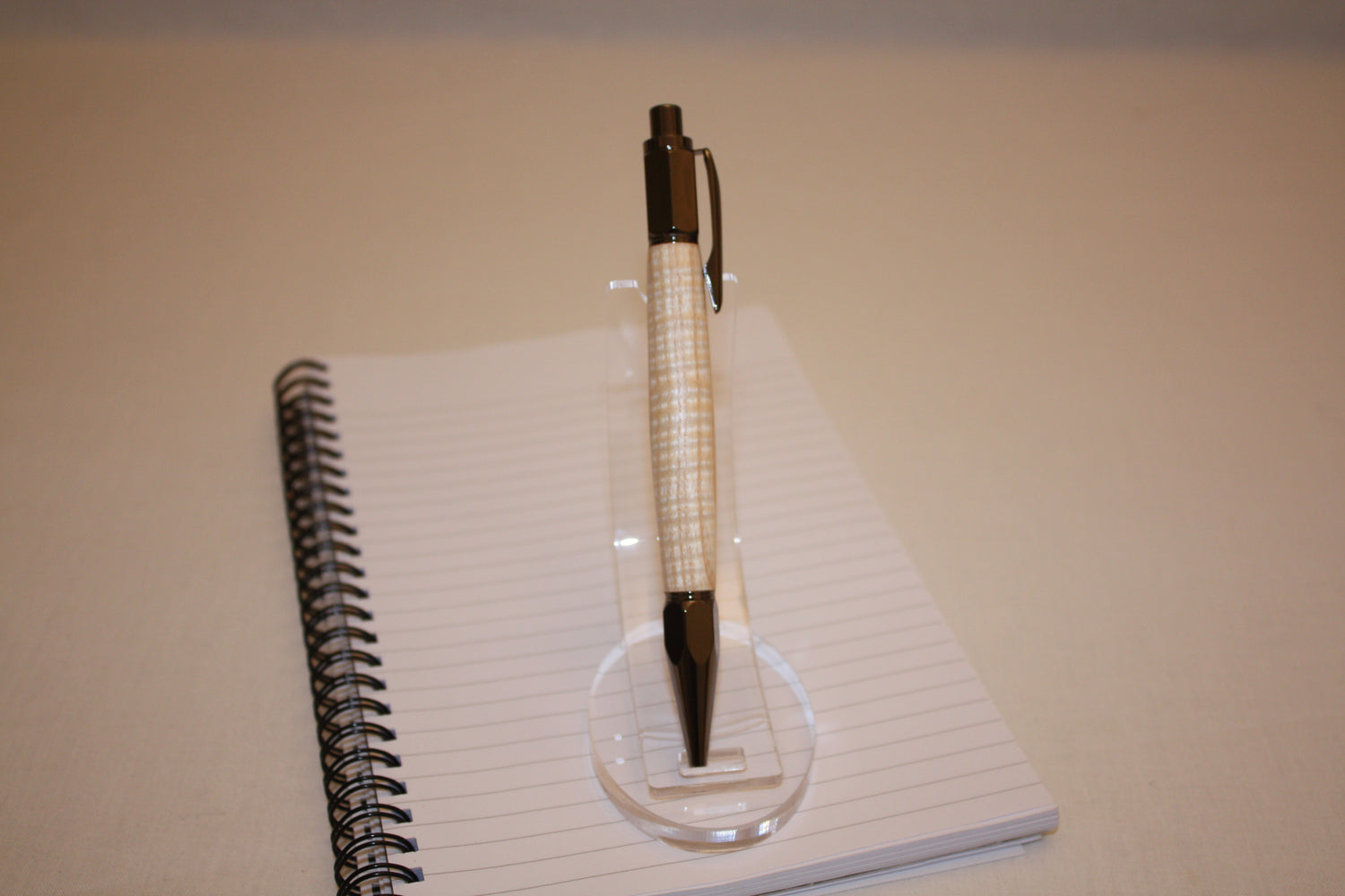 Stylo poussoir en frêne ondé. Ses extrémités ciselées offrent un grand confort d'écriture. Ce stylo a une écriture fine et utilise des recharges type Parker.