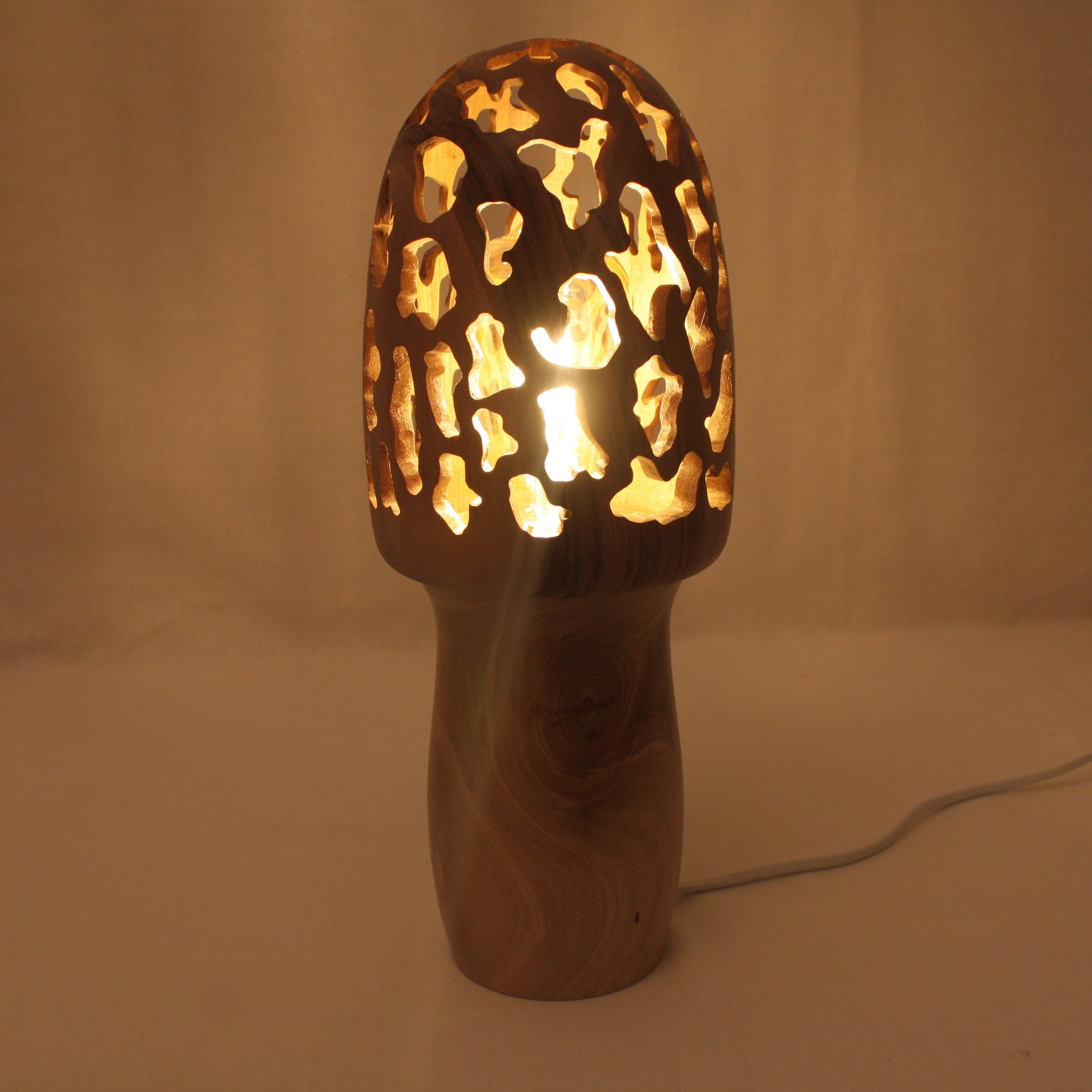 Lampe en forme de morille en noyer fabriqué entièrement à la main tourné puis sculté pour laisser sortir la lumière par le chapeau de la morille qui a une fonction d'abat jour.
Lampe de 35 cm de hauteur.
