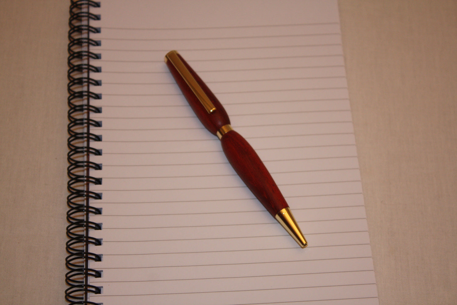 Stylo très élégant en bois de padouk fabriqué de façon artisanale. Ce stylo a une écriture noire.