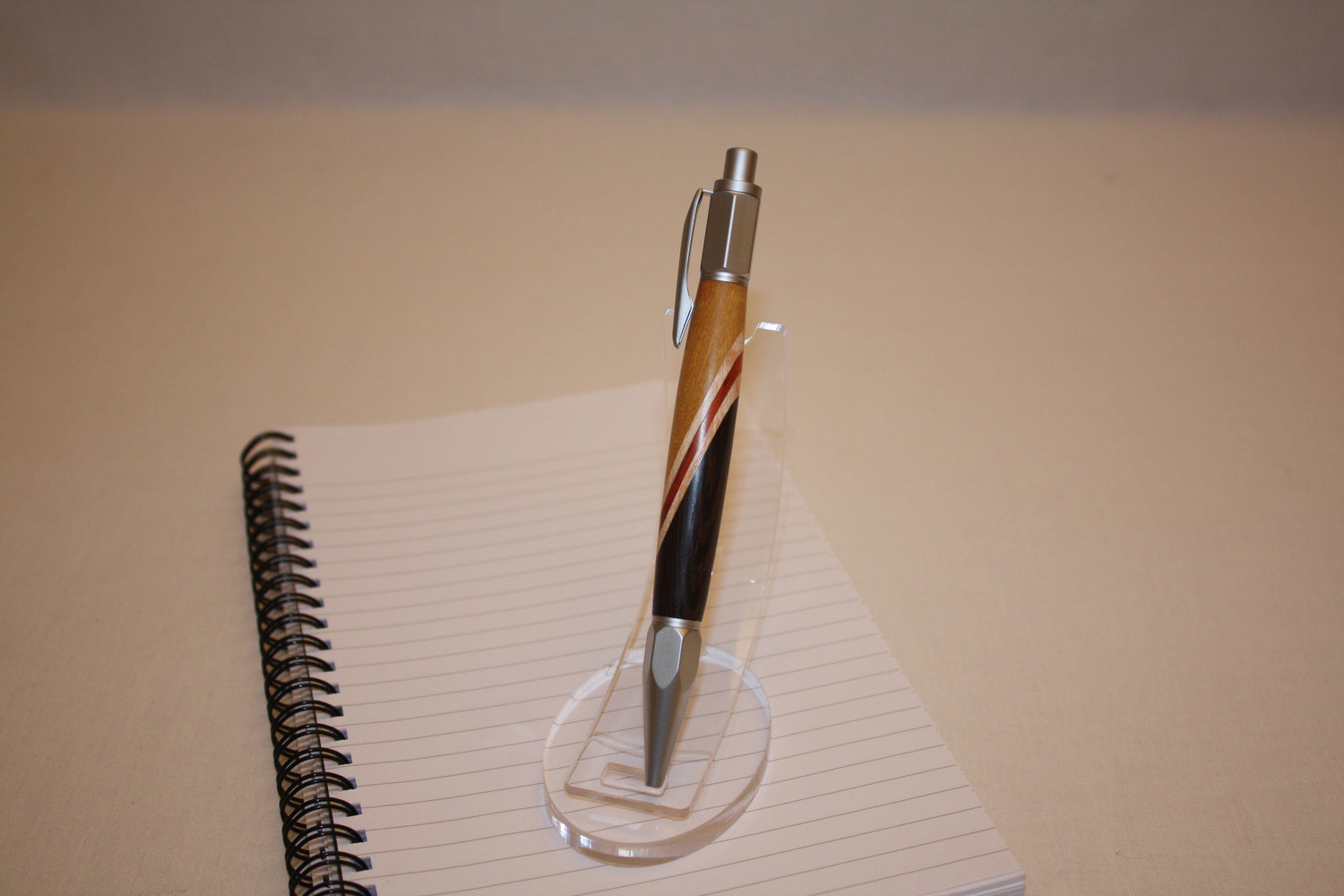 Stylo poussoir en collage de wengé,, frêne, padouf et citronier. Ses extrémités ciselées offrent un grand confort d'écriture. Ce stylo a une écriture fine et utilise des recharges type Parker.