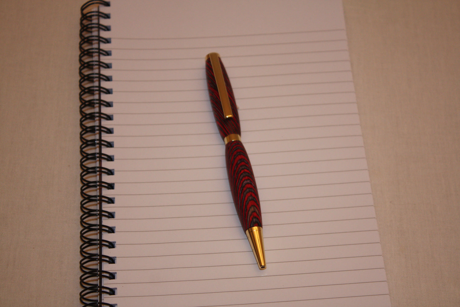 Stylo artisanal en lamelles de bois teintées et collées entre elles avant d'être coupées en diagonale. Le fait de couper les lamelles en diagonale lui donne cet aspect si particulier et si joli une fois la fabricaton terminée. Ce stylo a une écriture noire.