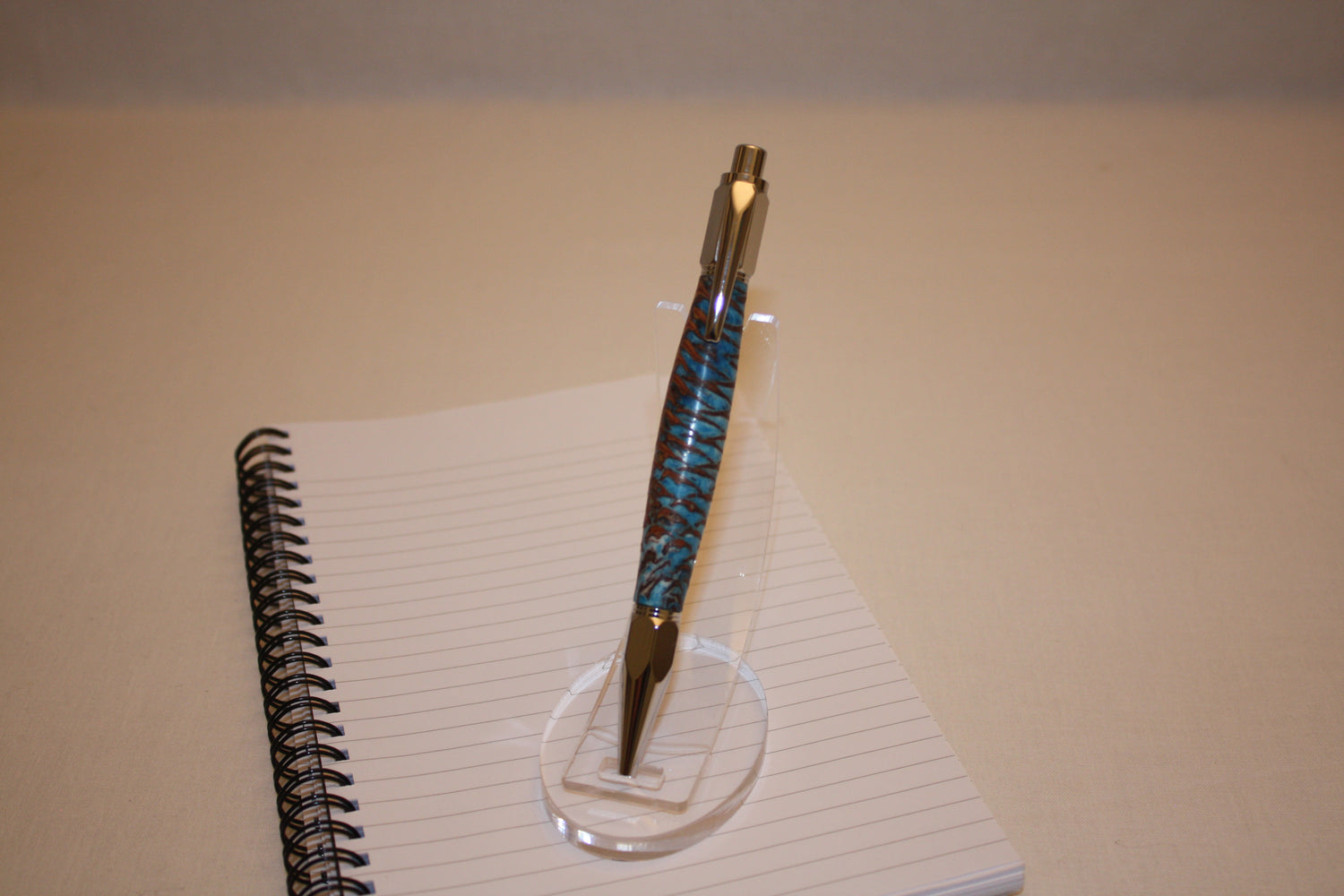 Stylo poussoir en pive de sapin et résine bleue et blanche. Ses extrémités ciselées offrent un grand confort d'écriture. Ce stylo a une écriture fine et utilise des recharges type Parker.