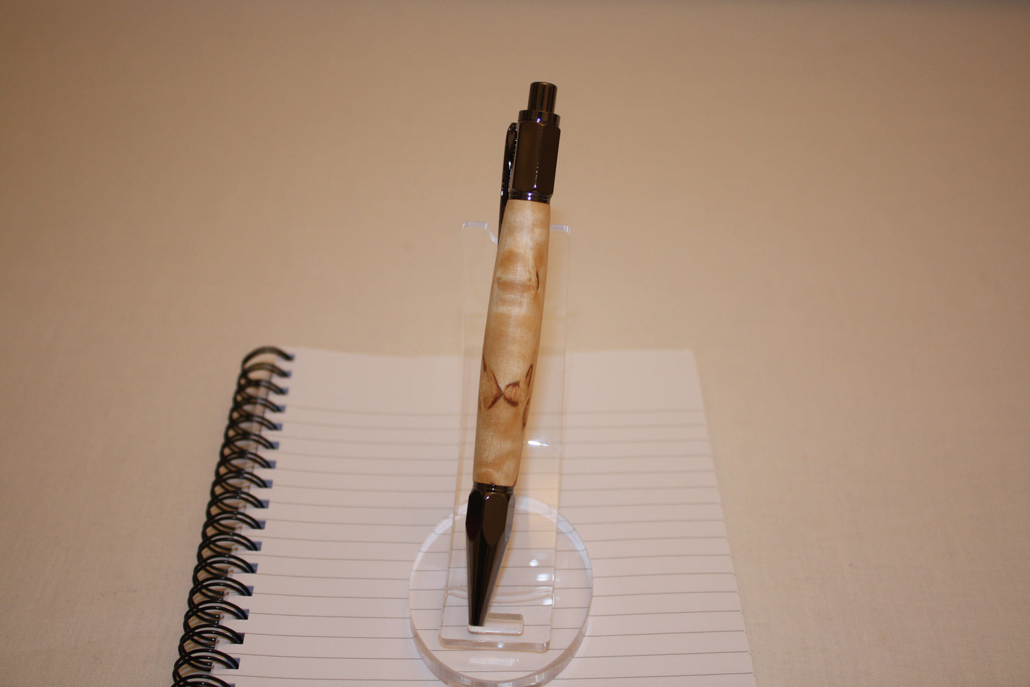 Stylo poussoir en bouleau madré. Ses extrémités ciselées offrent un grand confort d'écriture. Ce stylo a une écriture fine et utilise des recharges type Parker.