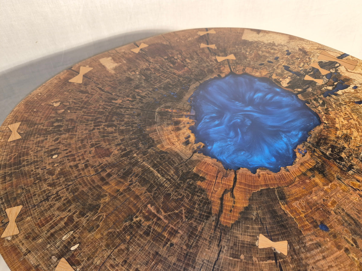 Table basse hêtre échauffé et résine bleue, piètement en métal.

Le plateau est issue d'une tranche de hêtre échauffé dont le milieu était creux, une bonne raison d'y ajouter de la résine !&nbsp;

Les noeuds papillons en chêne bien qu'ésthétiques sont aussi là pour empêcher que les fentes dans le bois ne progressent davantages.

La résine bleue métalisée donne de magnifiques reflets peu importe comment nous regardons la table.