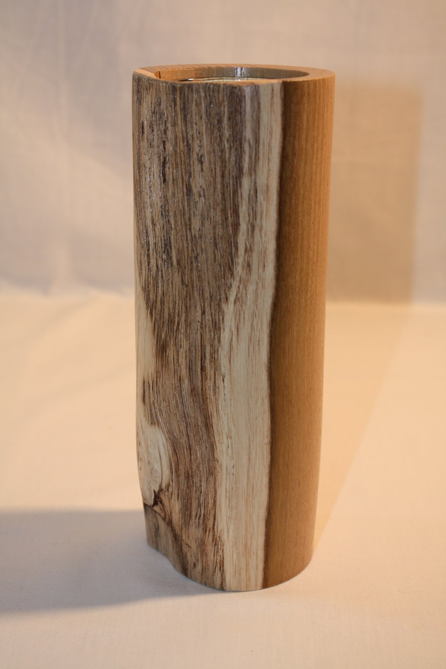 Vase en acacia tourné de manière artisanale. Celui-ci comprend un verre permettant d'y recevoir de l'eau pour les fleurs.