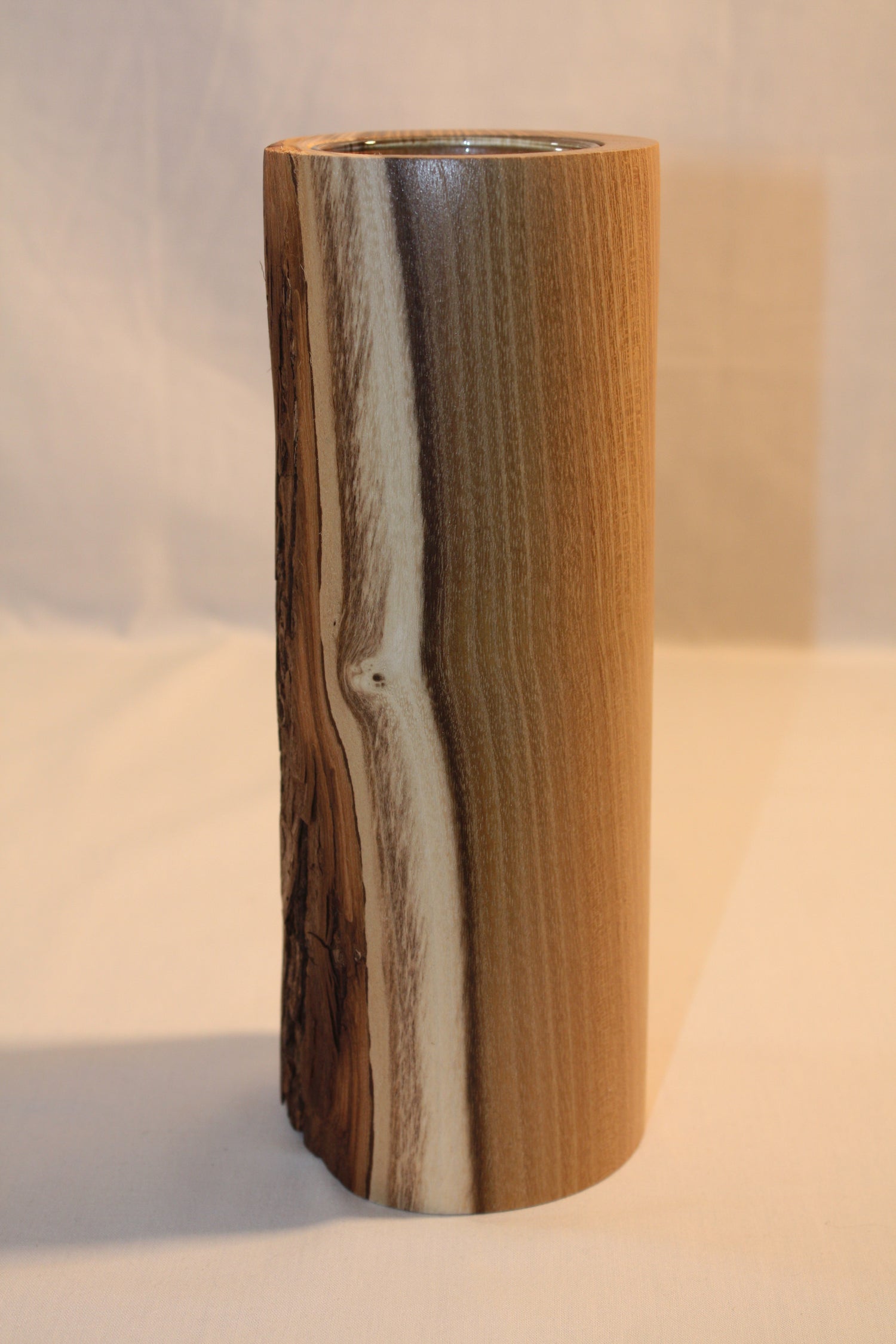 Vase artisanal en bois d'acacia avec écorce. Ce vase a été tourné a la main. Il comprend un verre ce qui permet d'y ajouter de l'eau pour les fleurs.